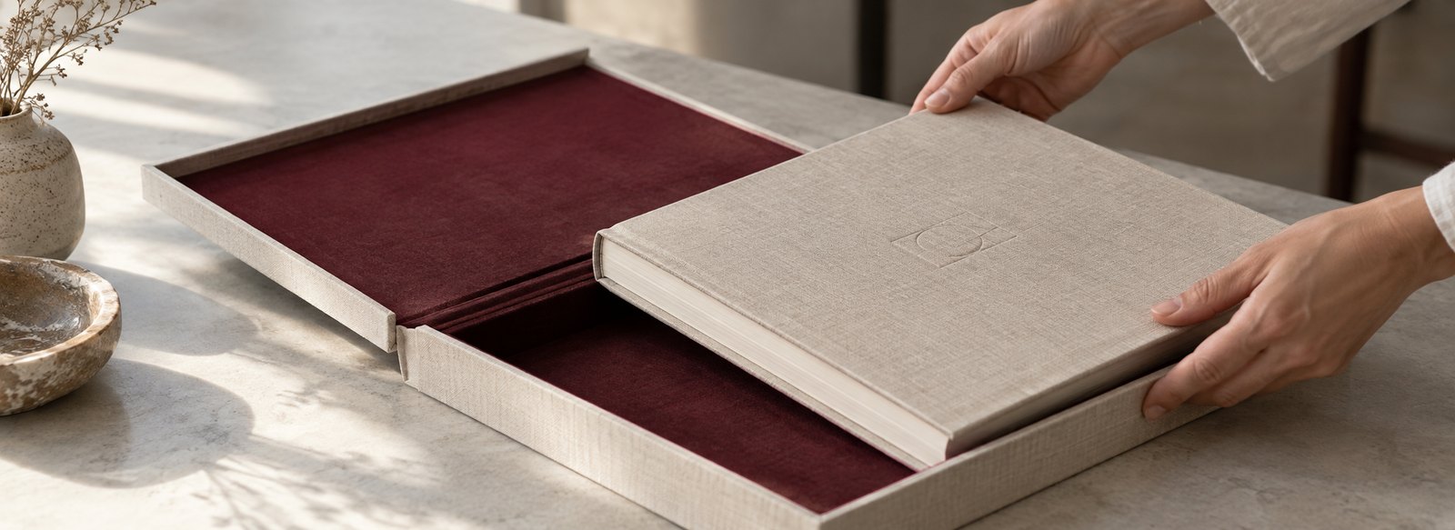 A clothbound book being lifted from its velvet-lined clamshell case
